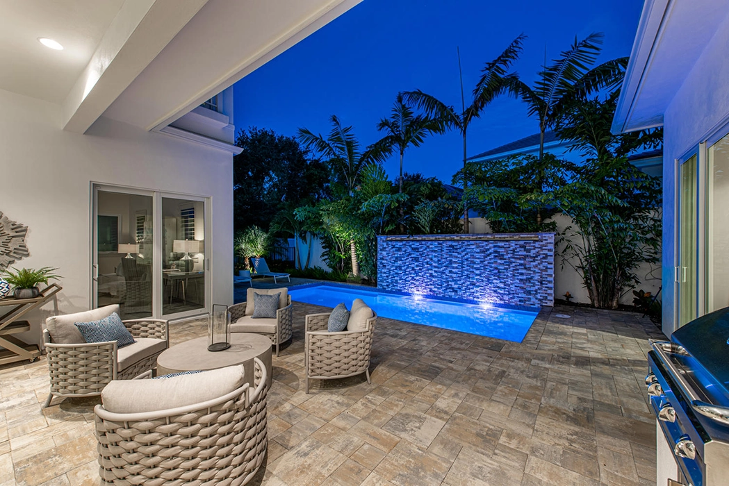 Nighttime backyard pool lit up with grill space